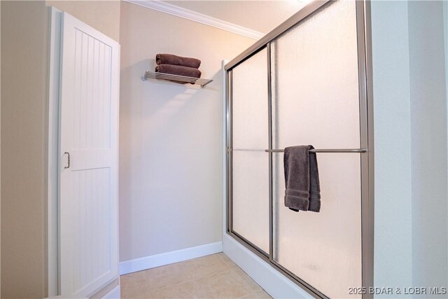 bathroom featuring tile patterned flooring, a stall shower, baseboards, and ornamental molding