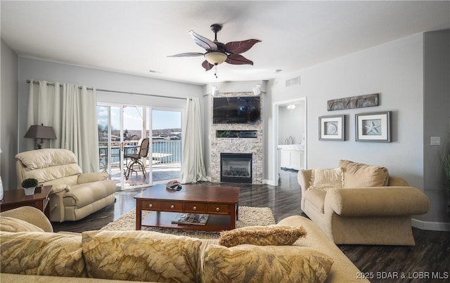 living room featuring visible vents, wood finished floors, a fireplace, baseboards, and ceiling fan