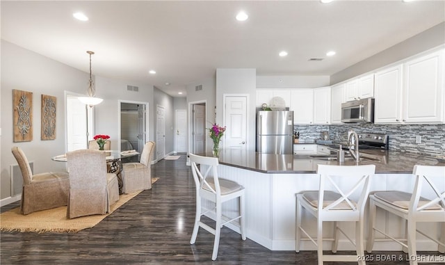 kitchen featuring visible vents, backsplash, a peninsula, and stainless steel appliances