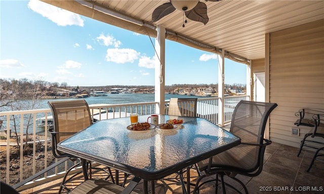 deck with outdoor dining area, a water view, and a ceiling fan