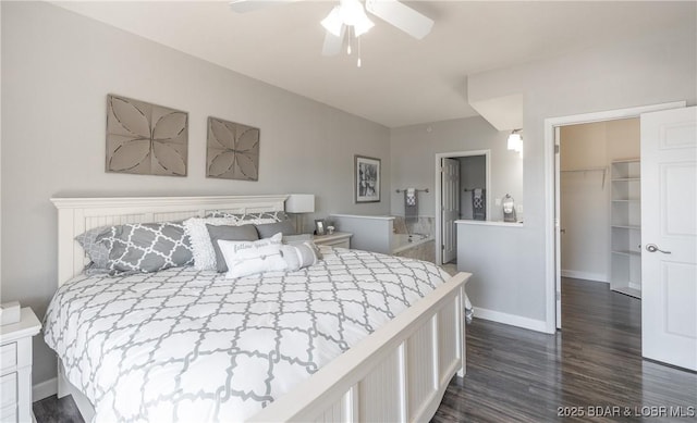 bedroom with ensuite bathroom, dark wood finished floors, baseboards, ceiling fan, and a spacious closet