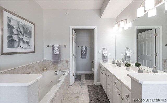 full bathroom featuring toilet, double vanity, a whirlpool tub, marble finish floor, and a sink