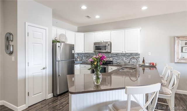 kitchen with a sink, stainless steel appliances, dark countertops, and decorative backsplash