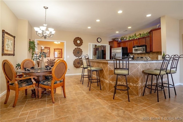 kitchen featuring a breakfast bar, brown cabinetry, tasteful backsplash, and appliances with stainless steel finishes