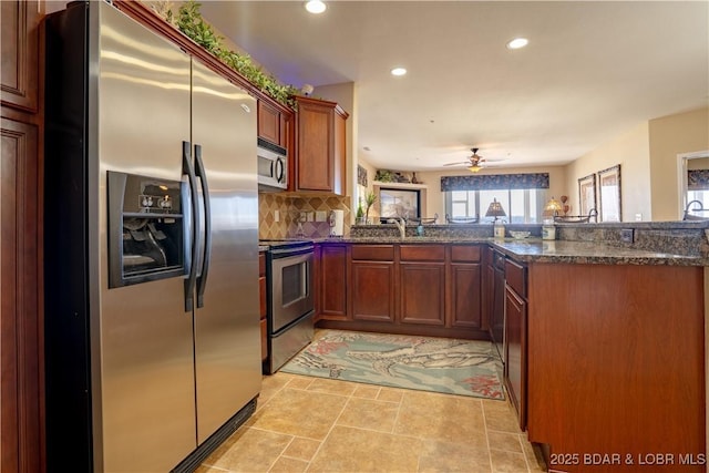 kitchen featuring a peninsula, dark stone counters, recessed lighting, decorative backsplash, and appliances with stainless steel finishes