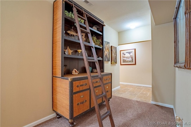 hall featuring baseboards, visible vents, and light carpet