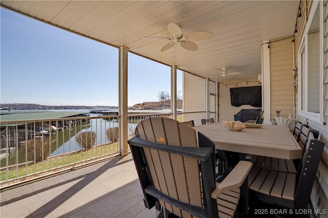 view of patio with a water view, outdoor dining space, and a ceiling fan