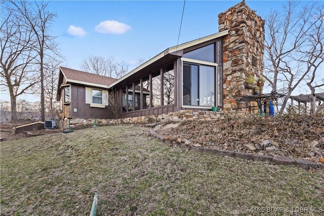 view of side of property featuring cooling unit, a chimney, and a yard