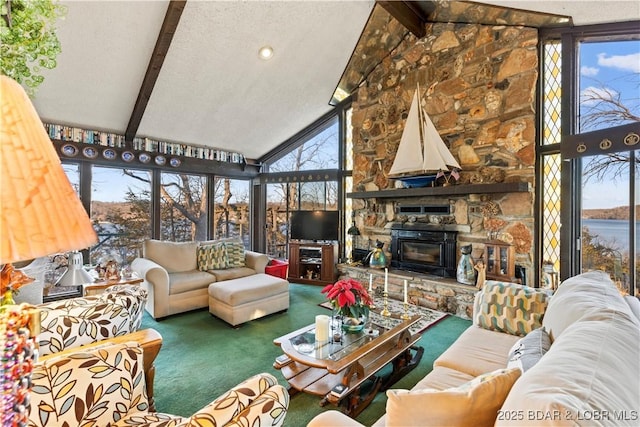 carpeted living room with a stone fireplace, beamed ceiling, and a healthy amount of sunlight