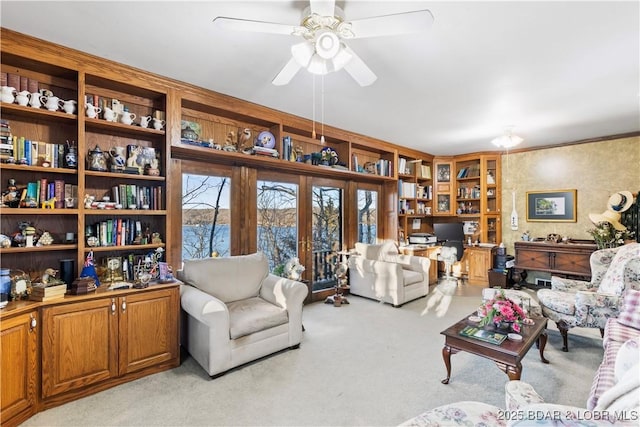 living area featuring light colored carpet and a ceiling fan