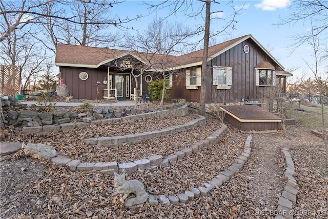 view of front of house with board and batten siding, a wooden deck, and roof with shingles