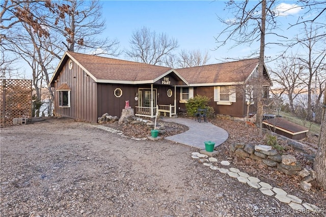 rustic home featuring a patio area, board and batten siding, driveway, and roof with shingles