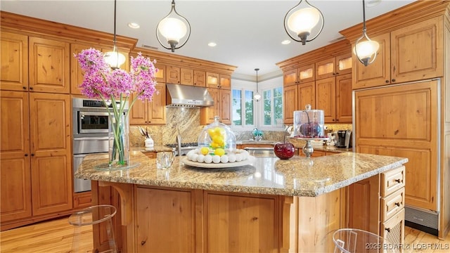 kitchen featuring an island with sink, under cabinet range hood, backsplash, glass insert cabinets, and light stone countertops