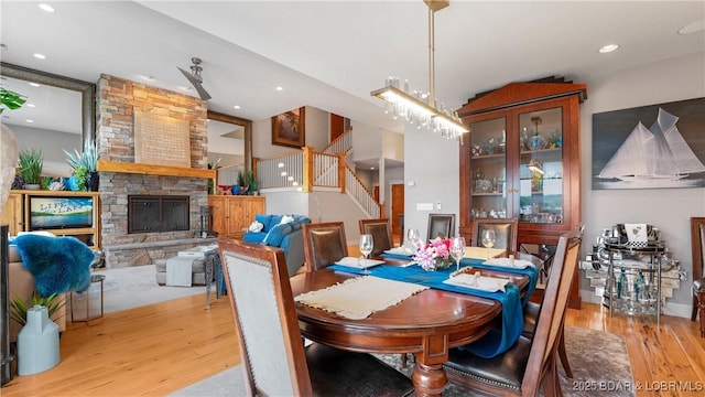 dining area with recessed lighting, a fireplace, wood finished floors, and stairs