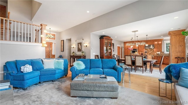 living area with recessed lighting, light wood-type flooring, and an inviting chandelier