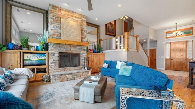 living area featuring ceiling fan with notable chandelier, wood finished floors, recessed lighting, stairway, and a fireplace