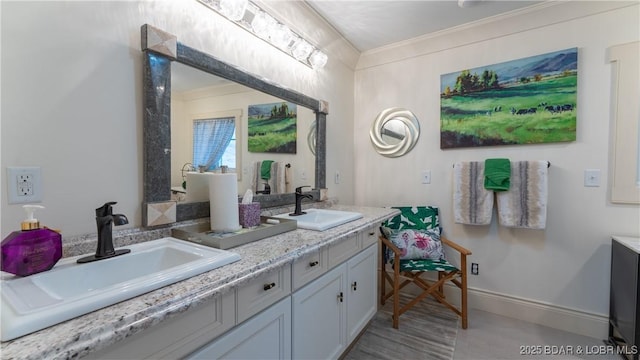 bathroom featuring double vanity, crown molding, baseboards, and a sink