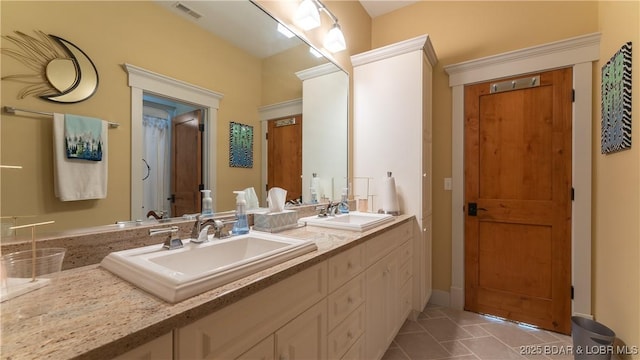 full bath with double vanity, visible vents, and a sink