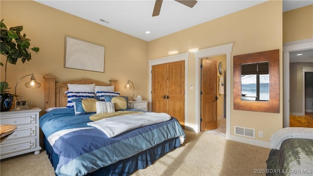 bedroom with visible vents, baseboards, light colored carpet, and ceiling fan