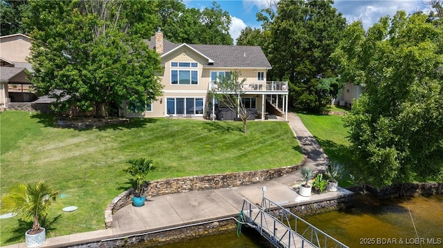 back of house featuring stairs, a chimney, a yard, a deck with water view, and a patio