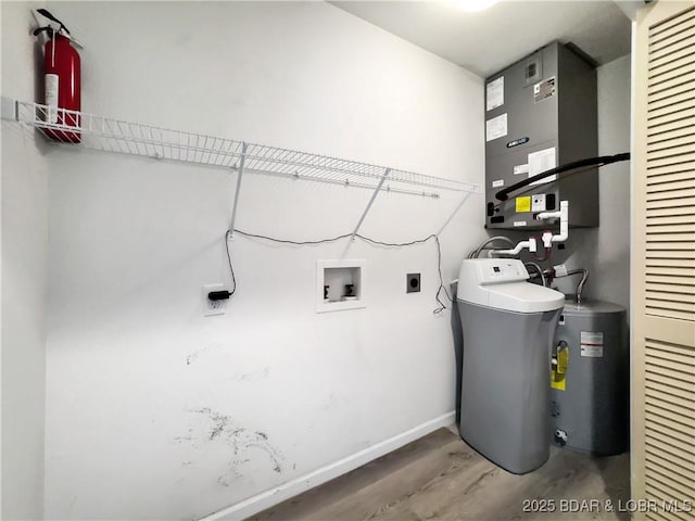 clothes washing area with electric water heater, wood finished floors, baseboards, hookup for an electric dryer, and hookup for a washing machine