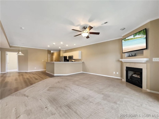 unfurnished living room with visible vents, crown molding, baseboards, a fireplace with flush hearth, and a ceiling fan