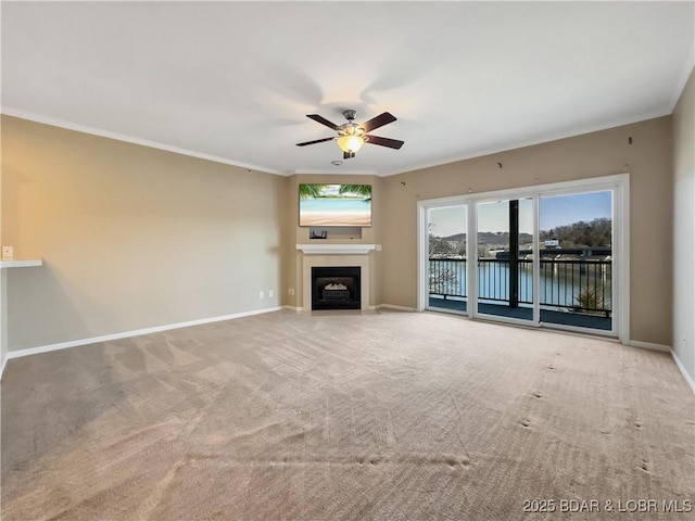 unfurnished living room with crown molding, baseboards, a water view, a fireplace, and a ceiling fan