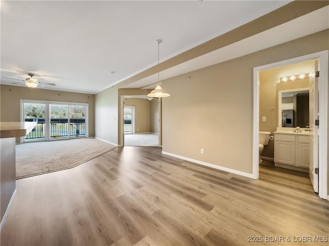 unfurnished living room with light wood-type flooring, baseboards, and ceiling fan