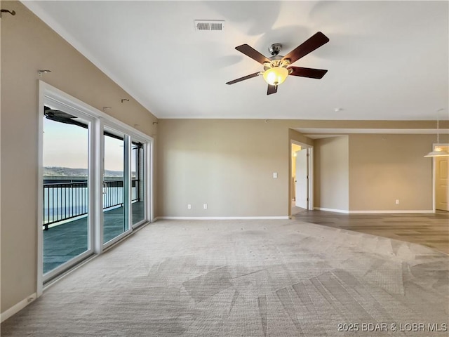 carpeted spare room featuring visible vents, baseboards, and ceiling fan