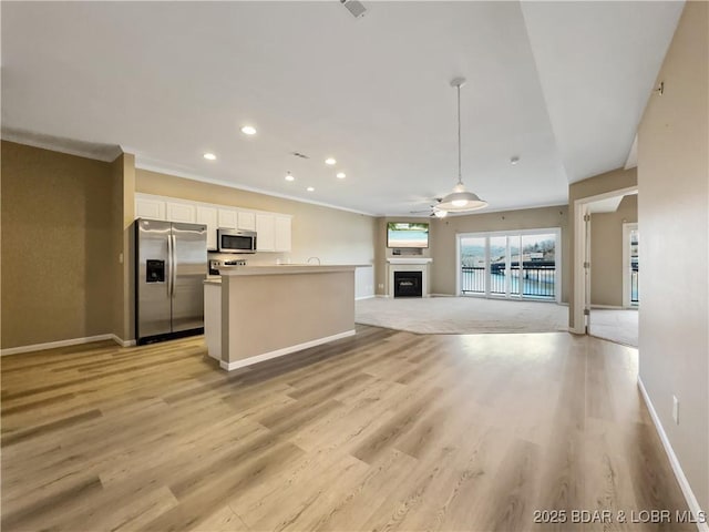 kitchen with light wood-style flooring, open floor plan, appliances with stainless steel finishes, white cabinets, and a fireplace