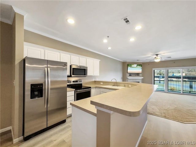 kitchen with visible vents, light countertops, a peninsula, stainless steel appliances, and a ceiling fan