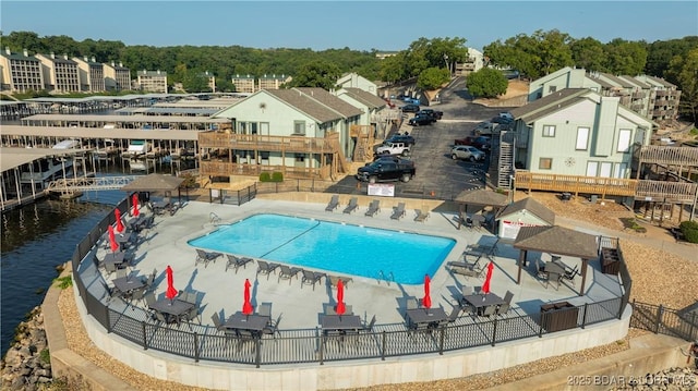 pool with a patio area, a water view, and fence