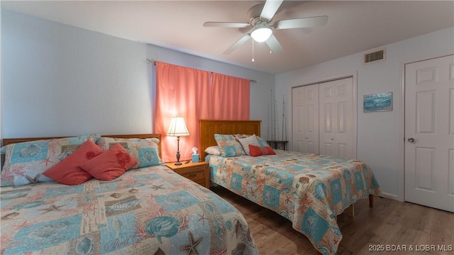 bedroom featuring a ceiling fan, wood finished floors, visible vents, and a closet