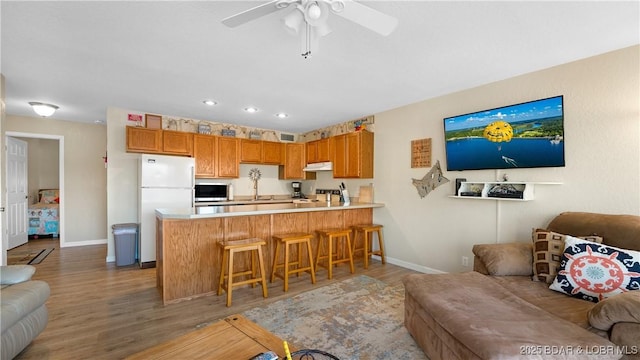 living area with recessed lighting, a ceiling fan, baseboards, and wood finished floors