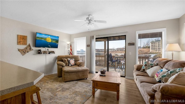 living area with baseboards, wood finished floors, and ceiling fan