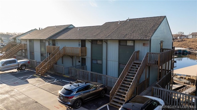 back of property featuring stairs and roof with shingles