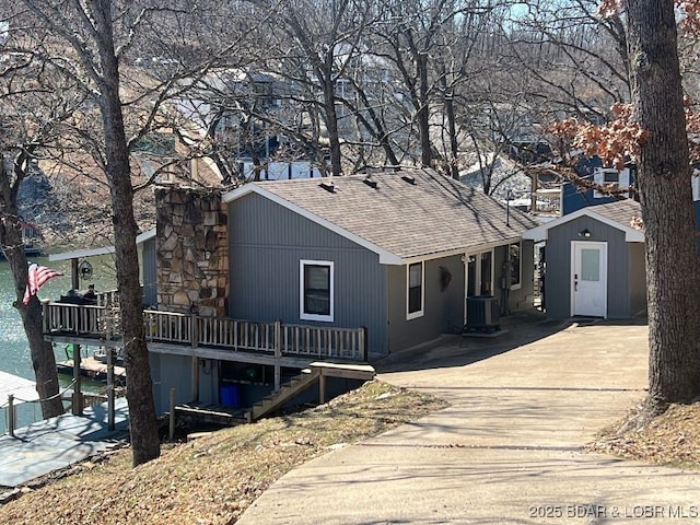 view of front of property with central AC, concrete driveway, a shingled roof, a wooden deck, and stairs