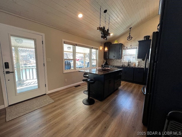 kitchen featuring a sink, wood finished floors, a center island, a breakfast bar area, and lofted ceiling