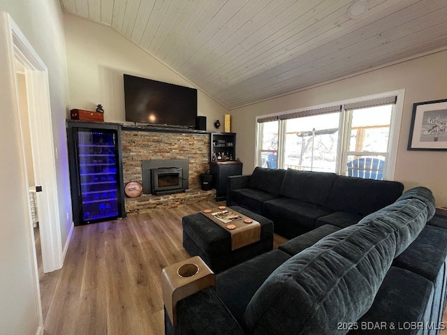 living room featuring beverage cooler, lofted ceiling, a stone fireplace, wooden ceiling, and wood finished floors