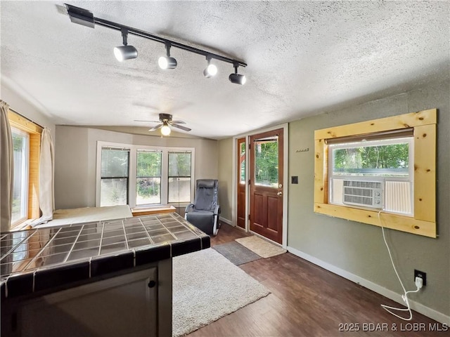 unfurnished living room featuring cooling unit, a ceiling fan, baseboards, dark wood finished floors, and a textured ceiling