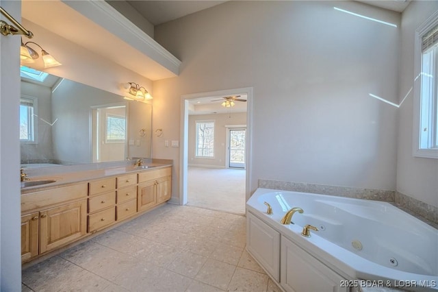 bathroom with ceiling fan, double vanity, a tub with jets, and a sink