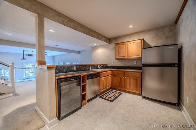 kitchen featuring beverage cooler, baseboards, a peninsula, a sink, and stainless steel appliances