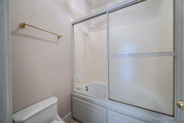 full bath featuring toilet and shower / bath combination with glass door