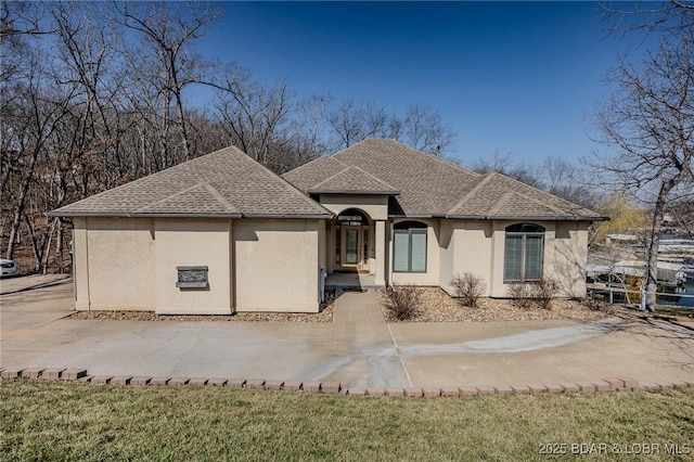 view of front of home featuring stucco siding and roof with shingles