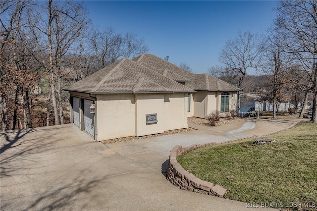 back of house with a shingled roof, stucco siding, concrete driveway, a garage, and a lawn