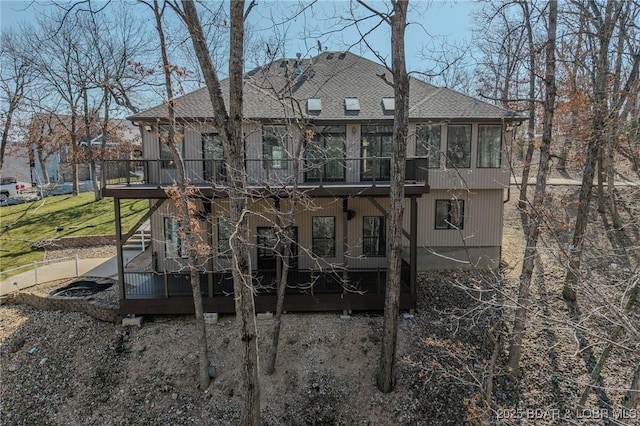 rear view of property with a shingled roof, a wooden deck, and a sunroom