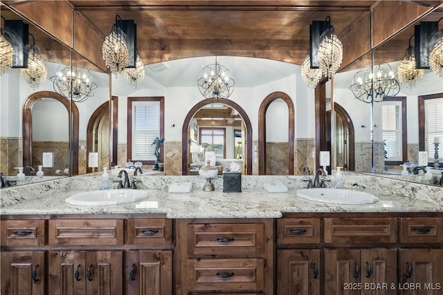 bathroom with double vanity, a notable chandelier, visible vents, and a sink