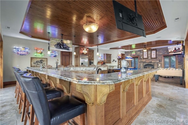 kitchen with visible vents, light stone countertops, stone finish floor, wood ceiling, and a tray ceiling