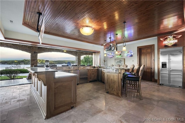 kitchen with a peninsula, hanging light fixtures, appliances with stainless steel finishes, a kitchen bar, and wooden ceiling