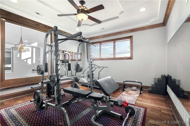 workout area featuring visible vents, wood-type flooring, crown molding, baseboards, and a ceiling fan